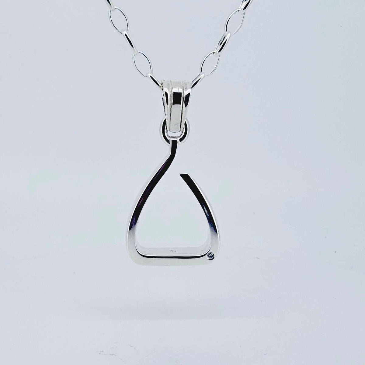 Product shot. Silver jump stirrup necklace. Set with one diamond. Based on the Freejump Stirrup. This is for Horse riders and equestrians. Made by Crawford Equestrian Jewellery.