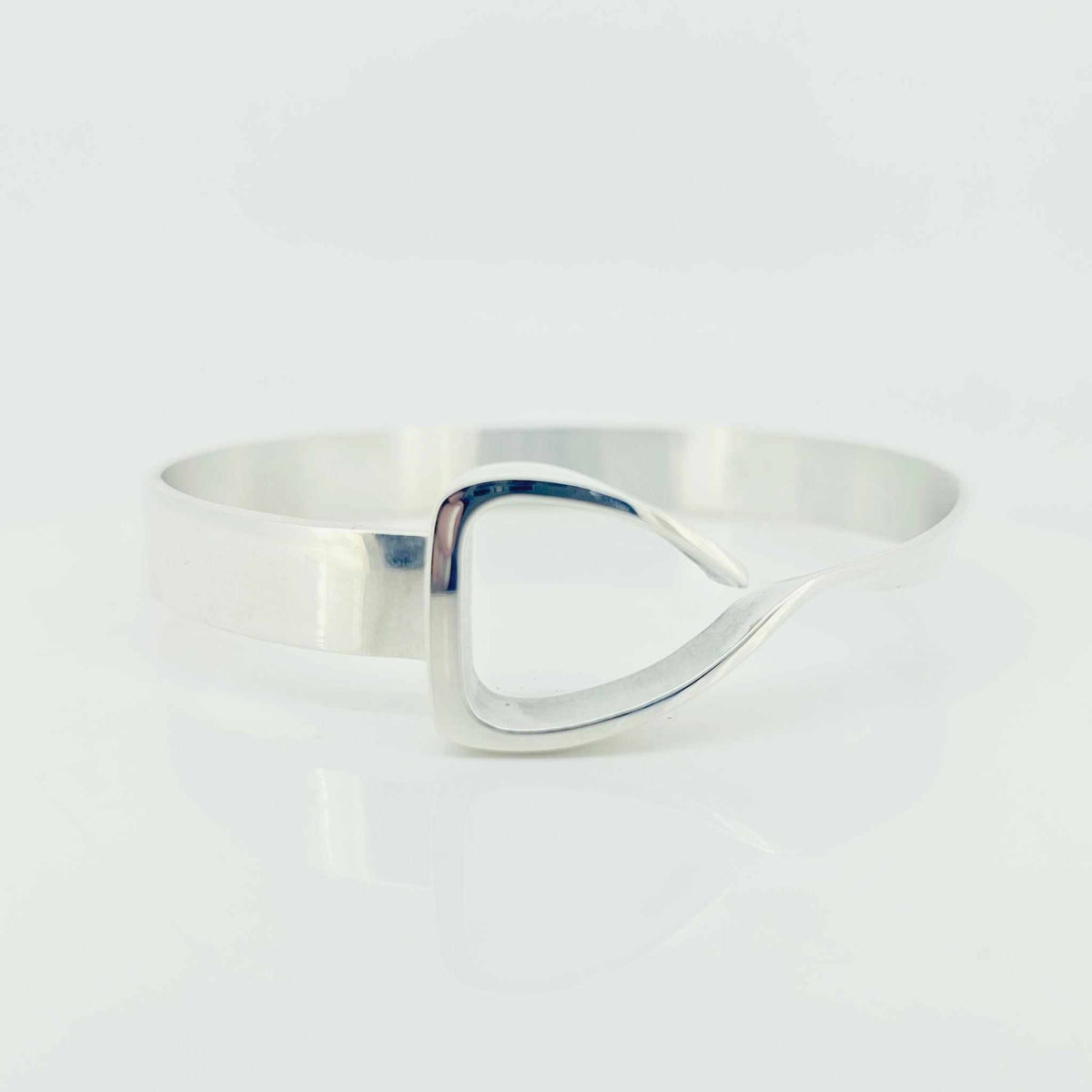 Equestrian Bangle in polished silver with a wide cuff and sculptural jump-stirrup-shaped centerpiece