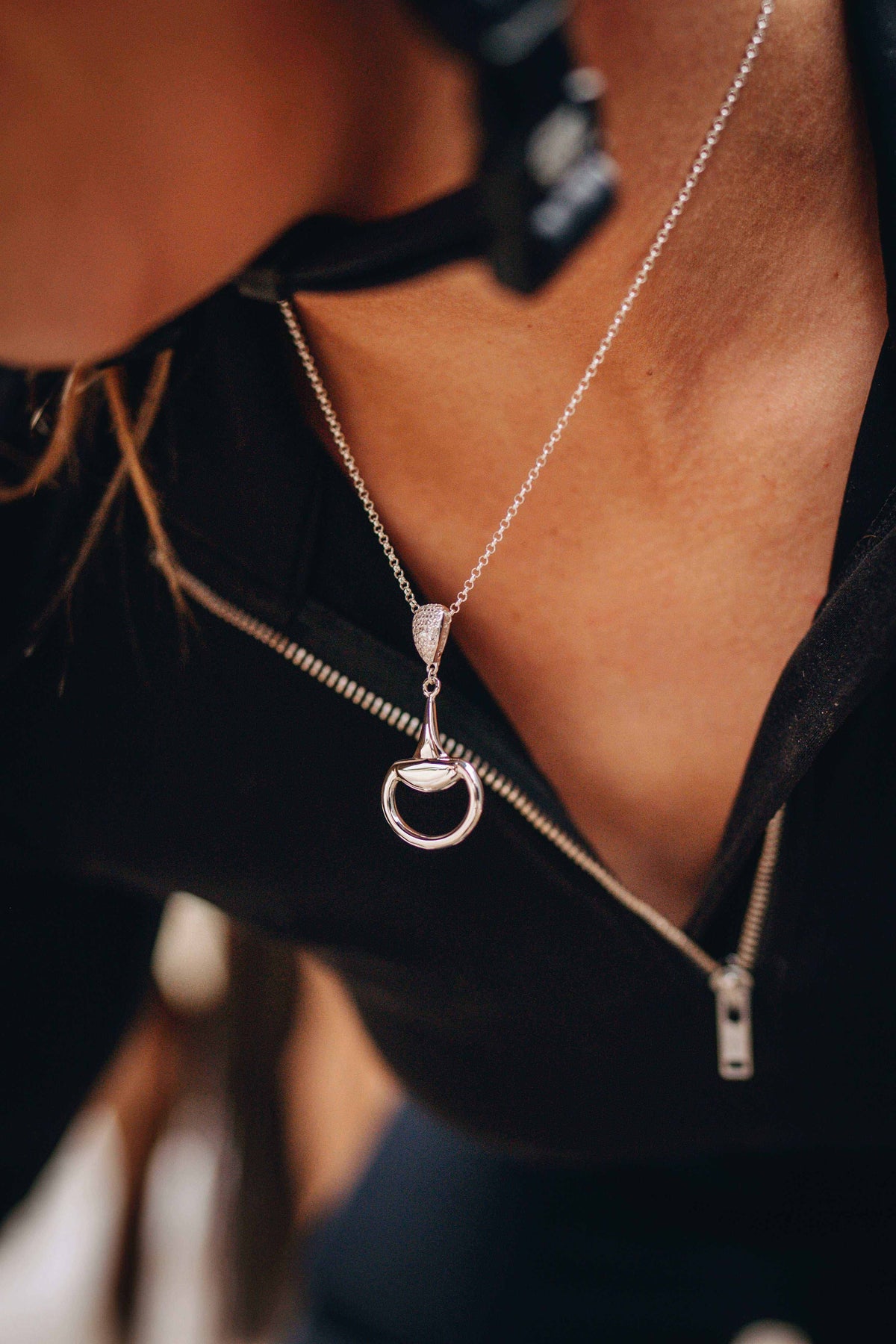 Equestrian Pendant in polished silver, featuring a delicate chain and a half-snaffle horse-bit design with a sparkling bale