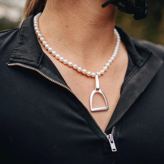 Pearl necklace with a polished silver stirrup pendant, a refined equine jewellery design combining classic equestrian style and lustrous beads