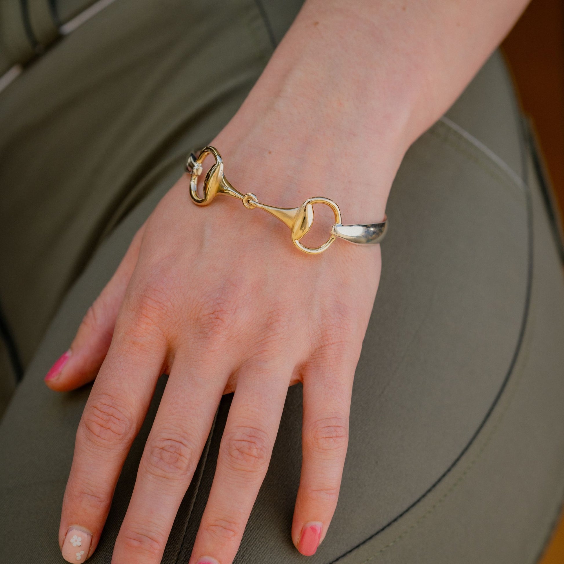 Gold horse bit snaffle bangle worn by girl wearing green breachers. Bangle made by Crawford Hill Equestrian Jewellery. 