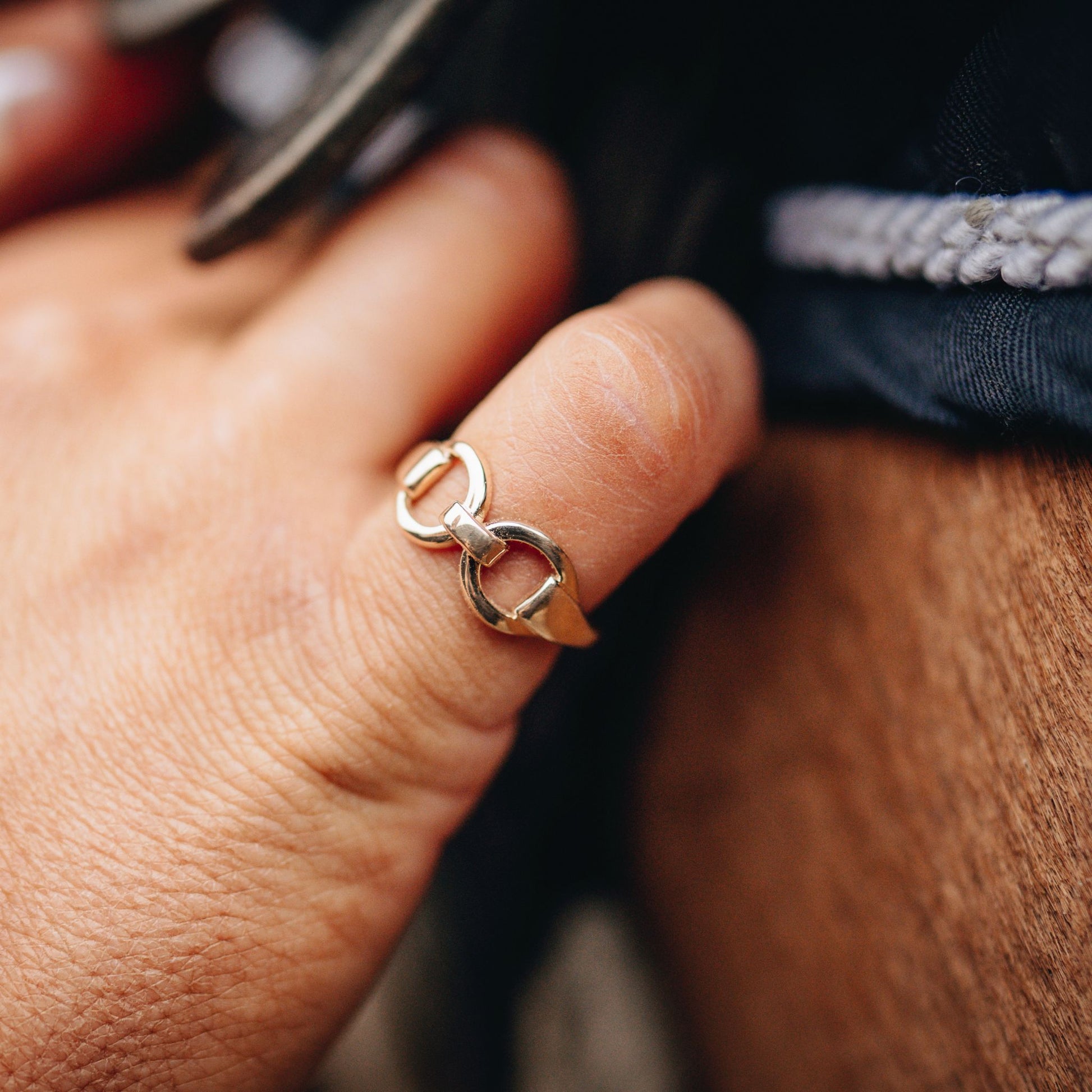 Horse rider going up the girth on her saddle. On her finger she has a gold horse bit snaffle ring made by Crawford Hill Equestrian Jewellery.