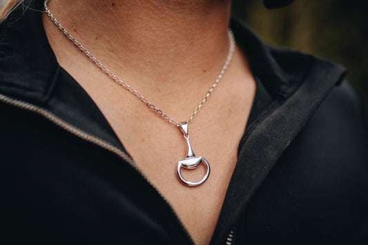 An equestrian wearing a Crawford Hill Half Snaffle Pendant in sterling silver. Paired perfectly with a sterling silver fine oval belcher chain. 