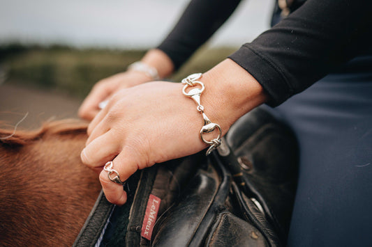 Snaffle Bracelet in polished silver with articulated horse-bit links, worn on the wrist beside a matching snaffle ring
