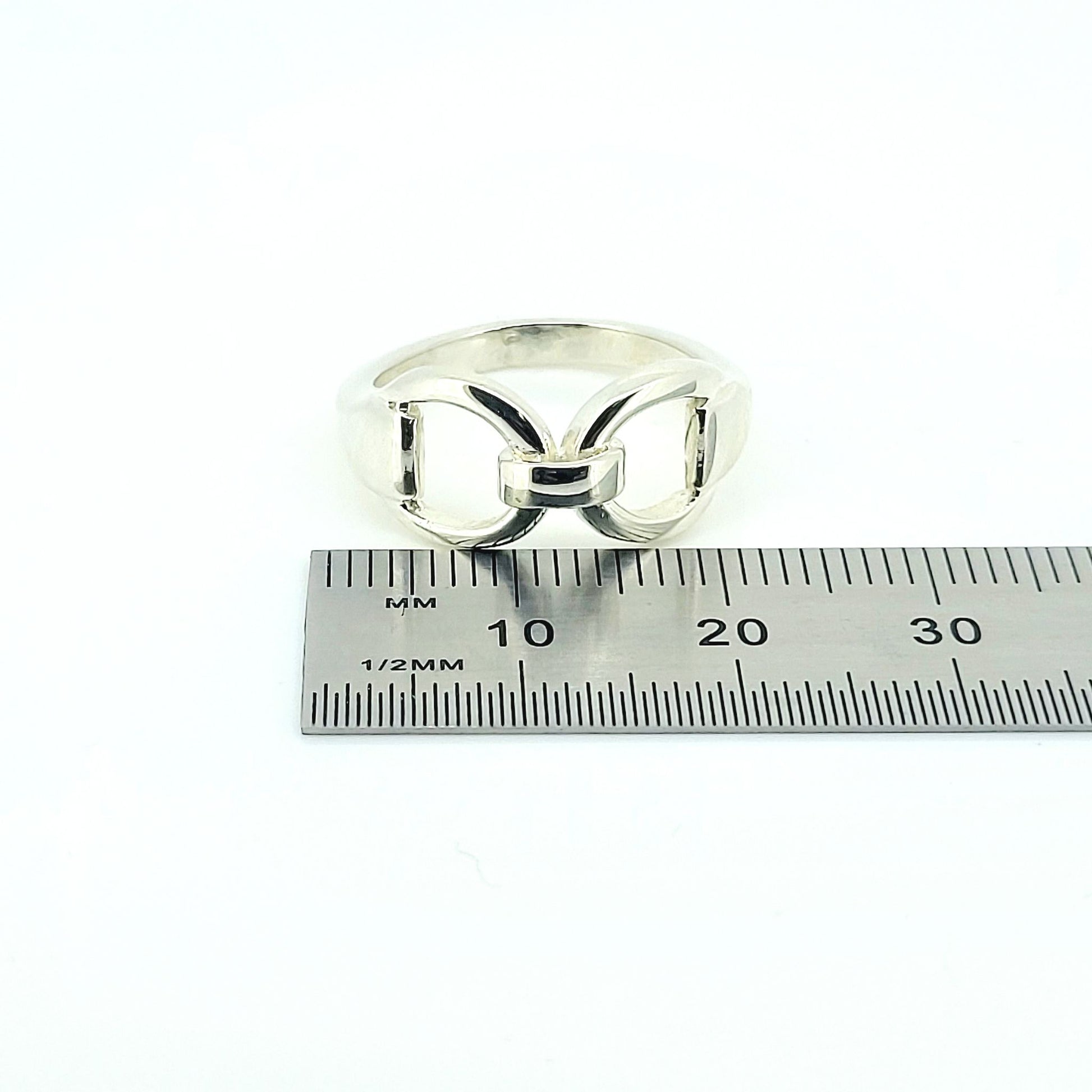 Product photo of a silver horse bit snaffle ring next to a silver ruler, showing size. The ring is made by Crawford Hill Equestrian Jewellery. 