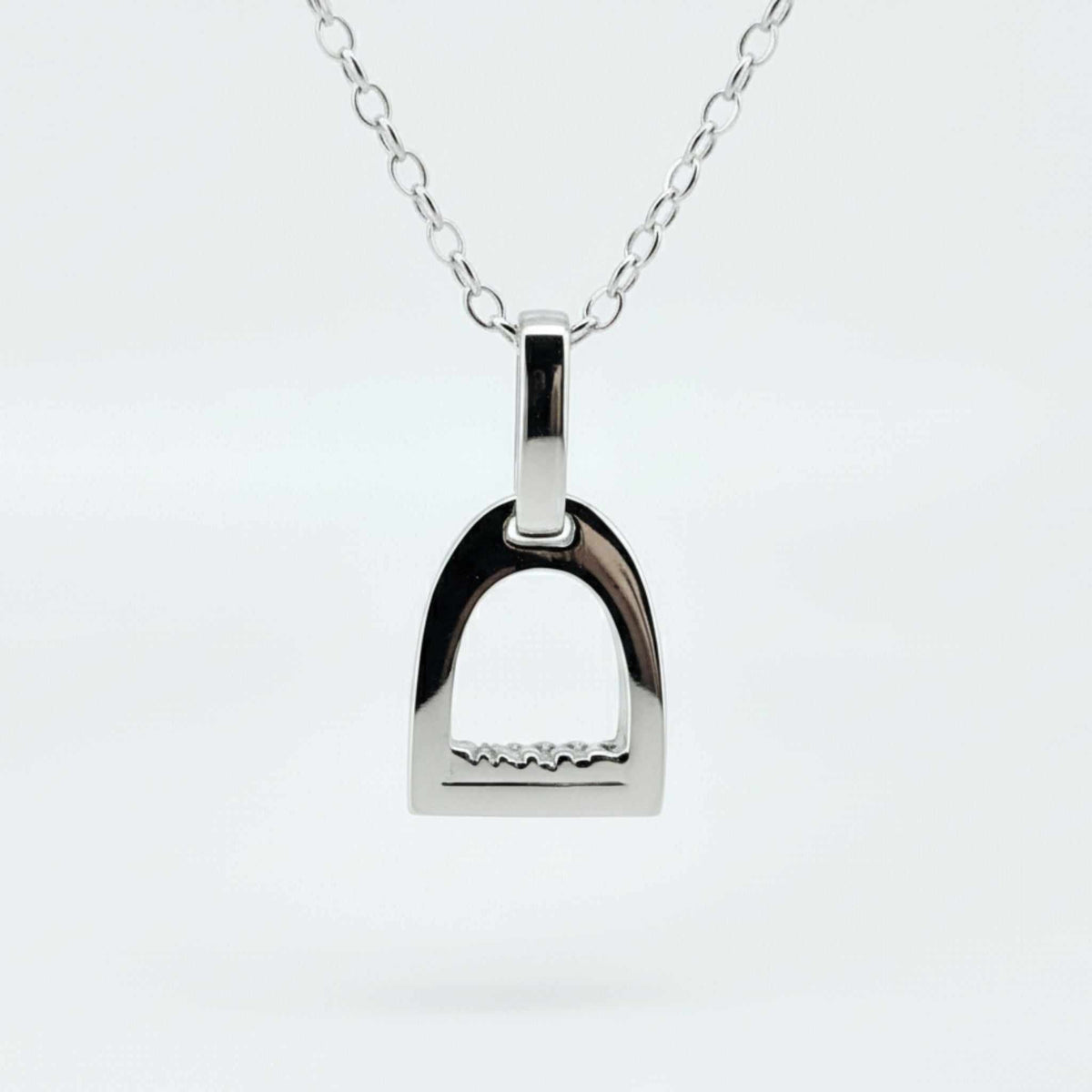 Stirrup Pendant in polished silver, featuring a classic English stirrup shape and a delicate chain attachment.